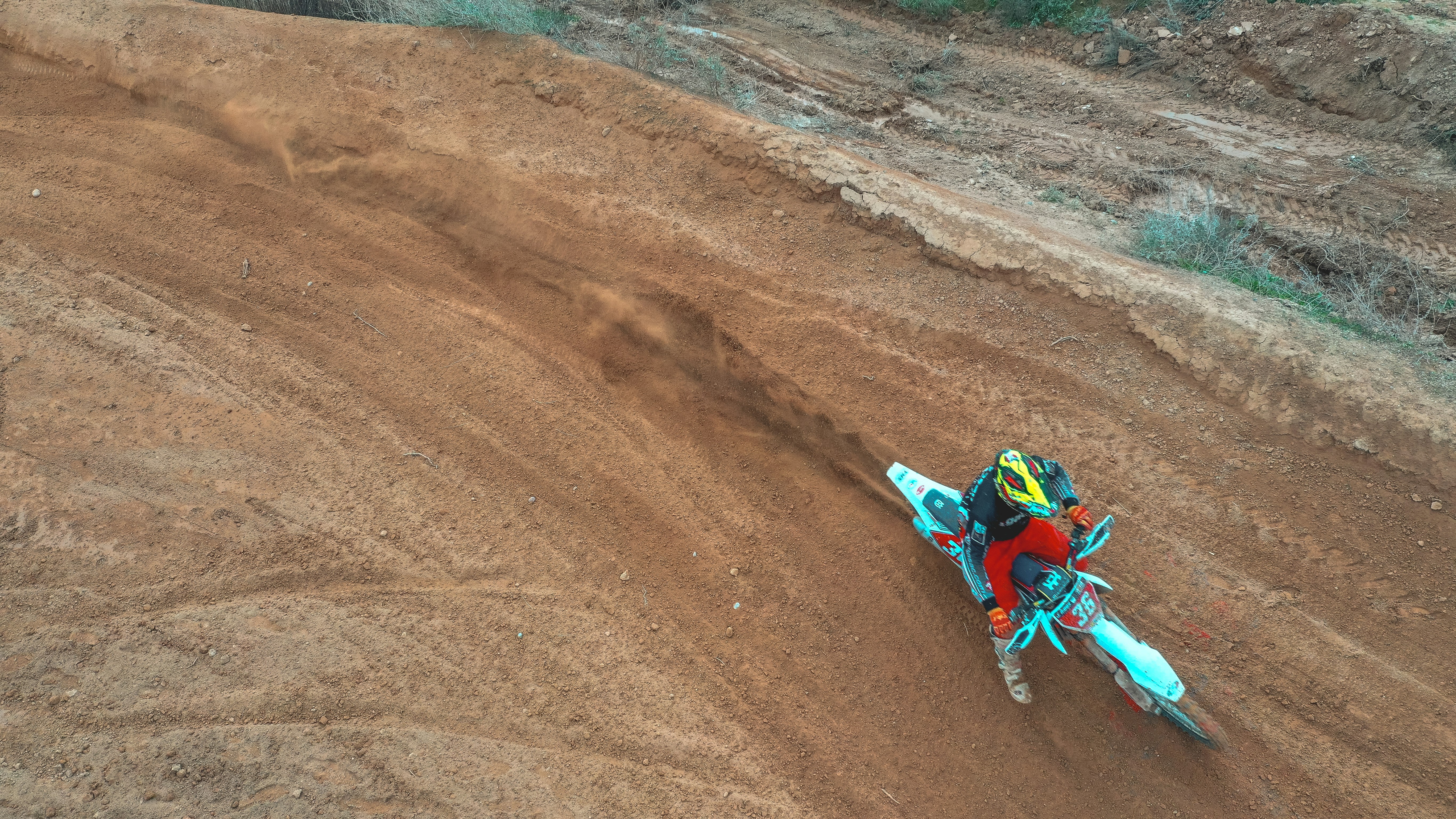 man riding motocross dirt bike on brown sand during daytime